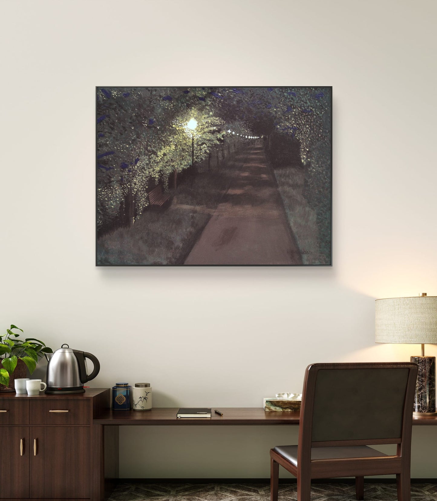 Framed artwork of a tree-lined path on a wall above a desk.